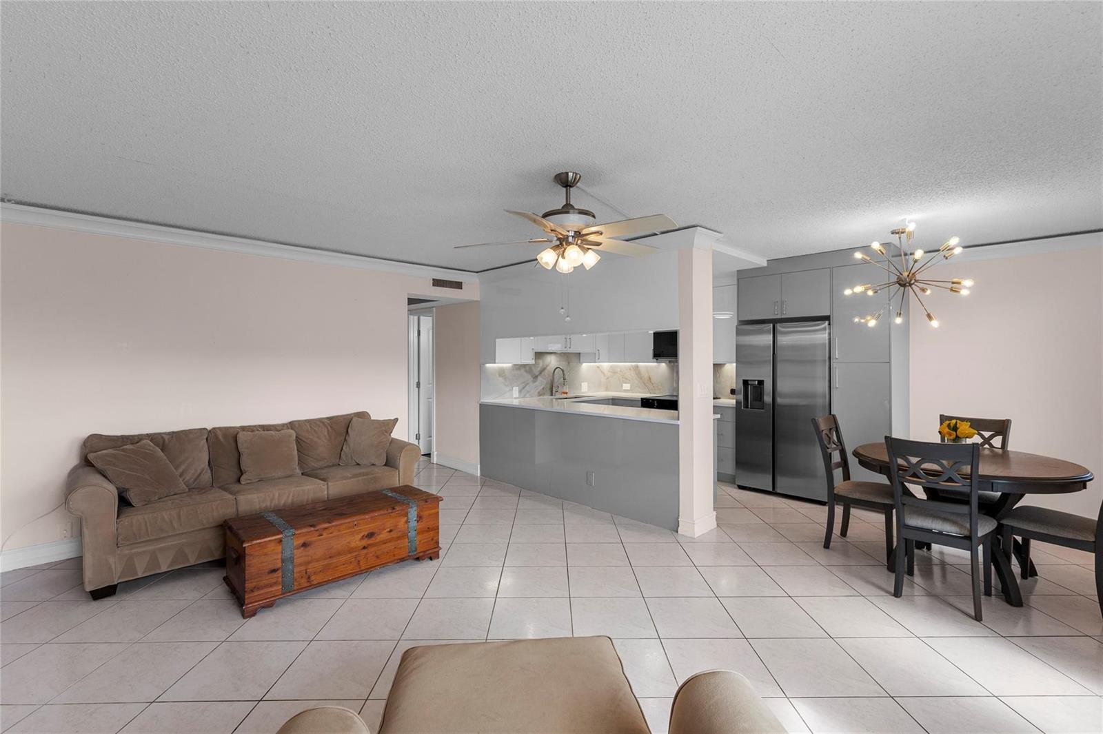A modern kitchen features gray cabinetry, white countertops, a stainless steel refrigerator, and tile flooring — 2122 Cambridge F # 2122, Deerfield Beach FL 33442, DEERFIELD BEACH, FL
