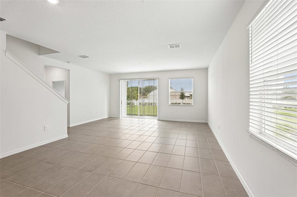 An empty living room features light-colored tile flooring, white walls, and a sliding glass door — 4606 OUTHAUL RUN, PALMETTO, FL