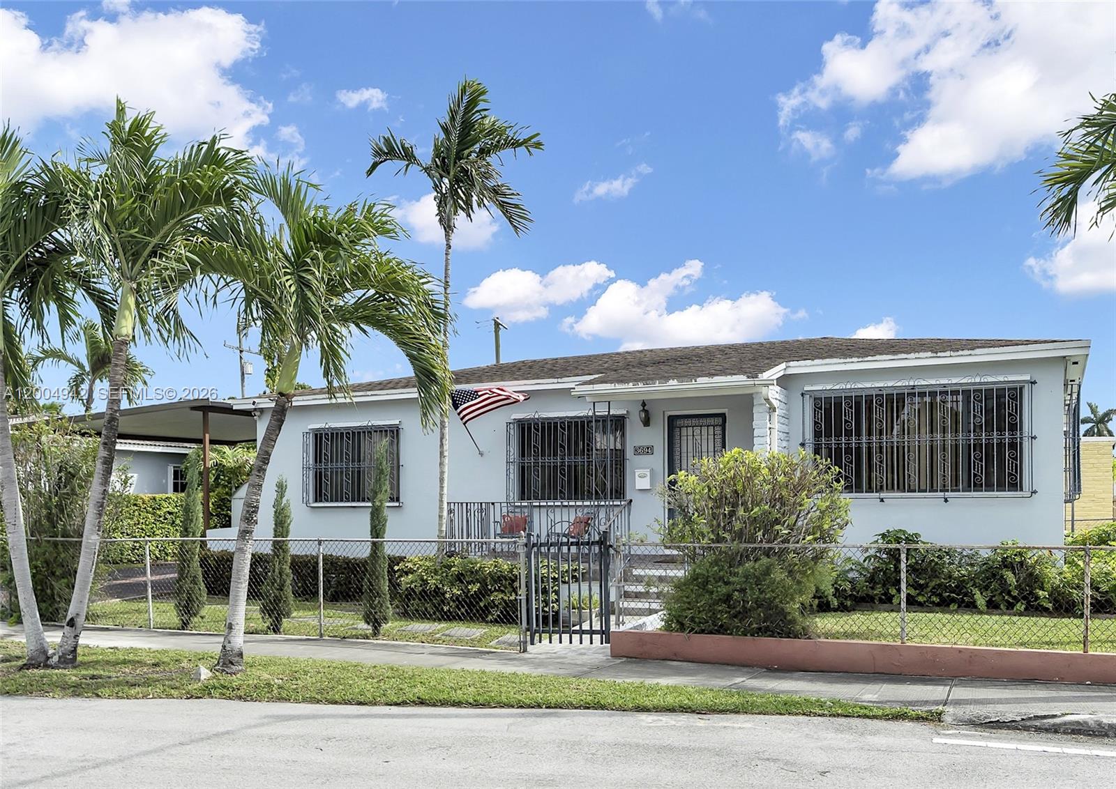 A single-story house with a light blue exterior, security bars on windows, and palm trees — 3694 NW 20th St, Miami FL 33142, MIAMI, FL