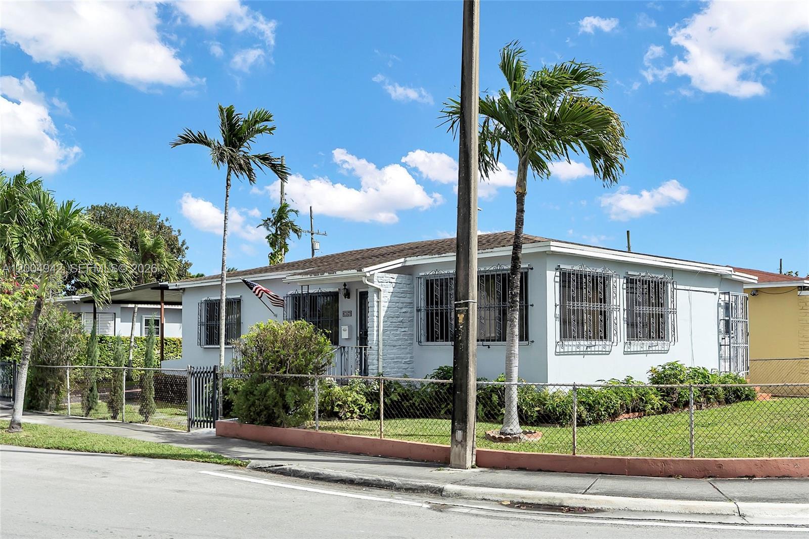 A single-story house with a light-colored exterior, security bars on windows, and palm trees — 3694 NW 20th St, Miami FL 33142, MIAMI, FL