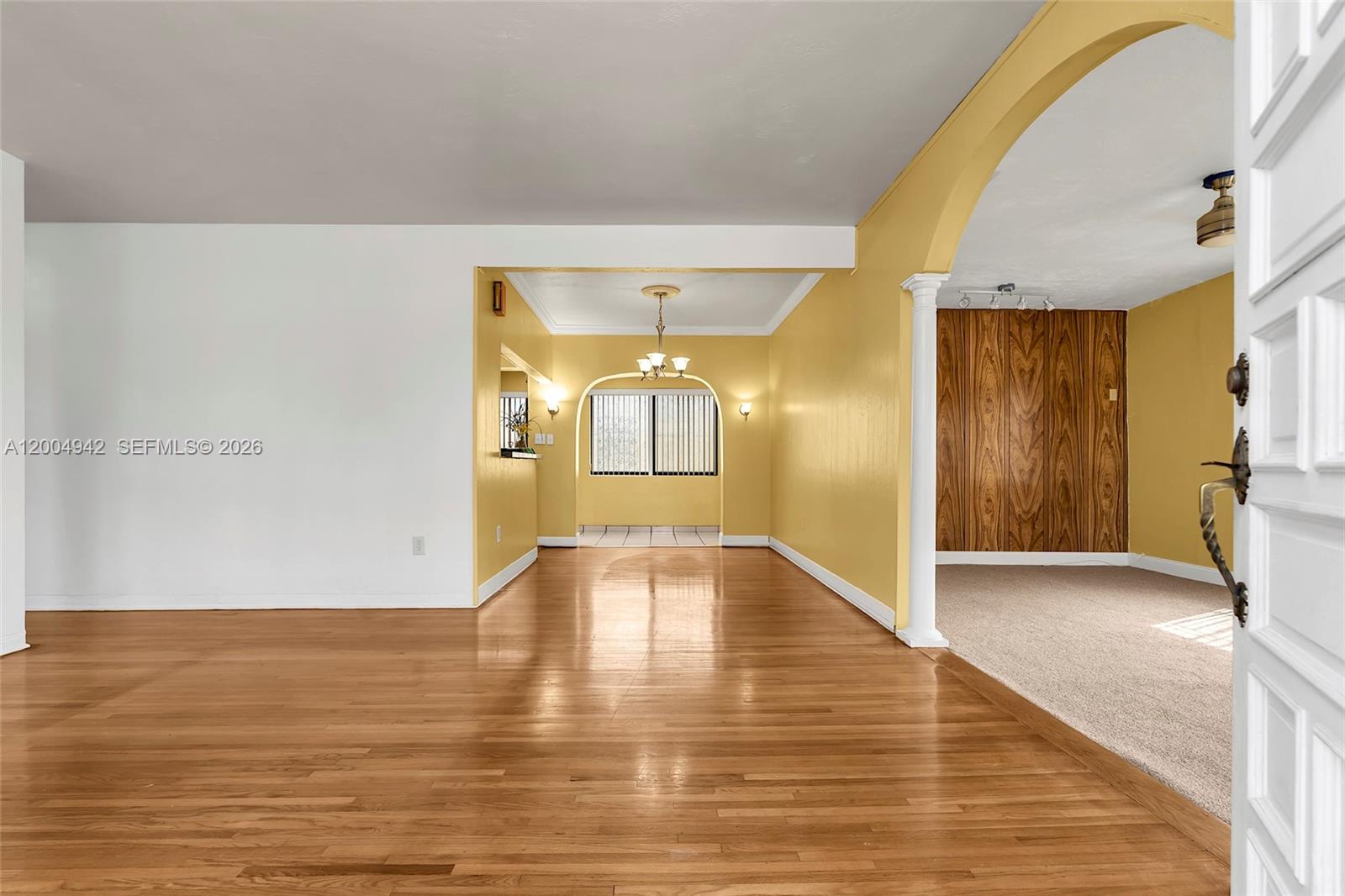 A living area with hardwood floors connects to a yellow dining room through an archway — 3694 NW 20th St, Miami FL 33142, MIAMI, FL