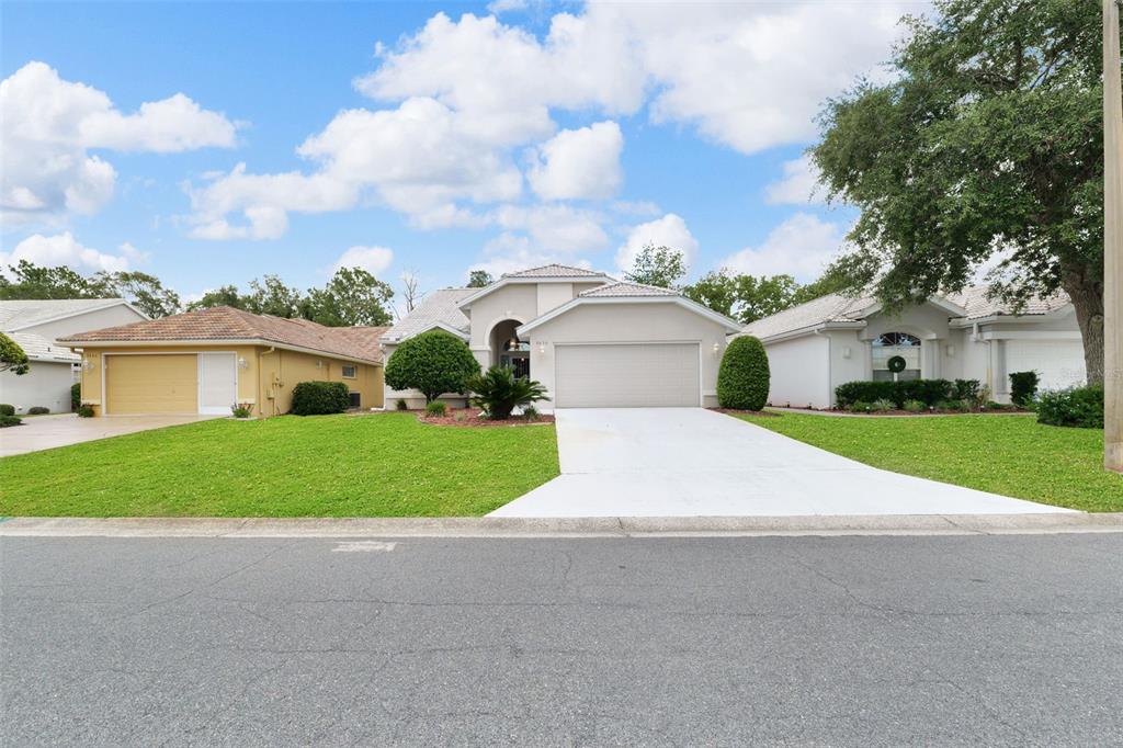 A beige single-story house with a two-car garage and a concrete driveway under a blue sky — 9450 MISSISSIPPI RUN, WEEKI WACHEE, FL