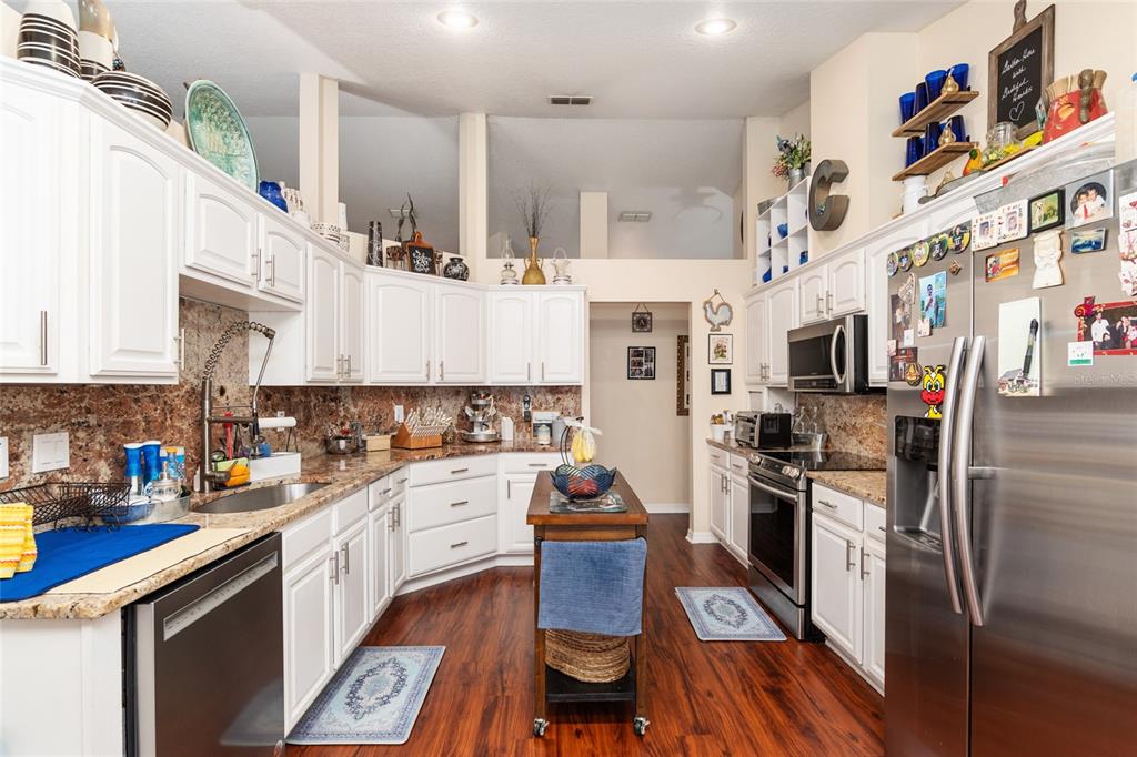 A kitchen with white cabinets, granite countertops, stainless steel appliances, and dark wood flooring — 275 SE 34TH PLACE, OCALA, FL