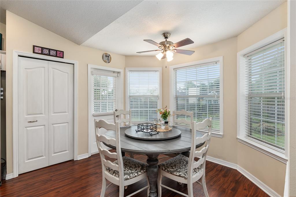 A dining area features a round wooden table, four chairs, a ceiling fan, and windows — 275 SE 34TH PLACE, OCALA, FL