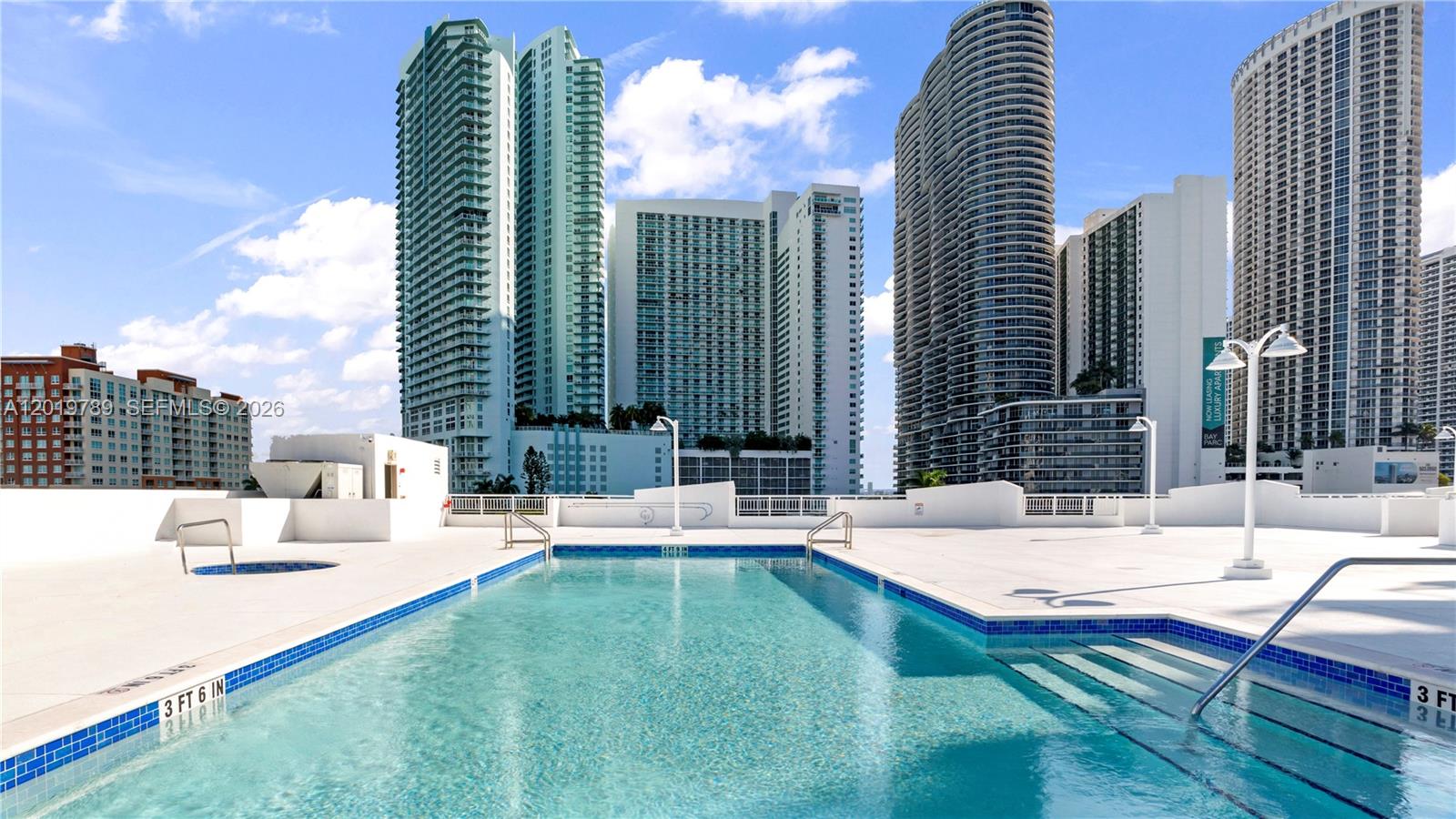 An outdoor swimming pool on a rooftop terrace surrounded by tall city high-rise buildings — 275 NE 18th st # 1606, Miami FL 33132, MIAMI, FL