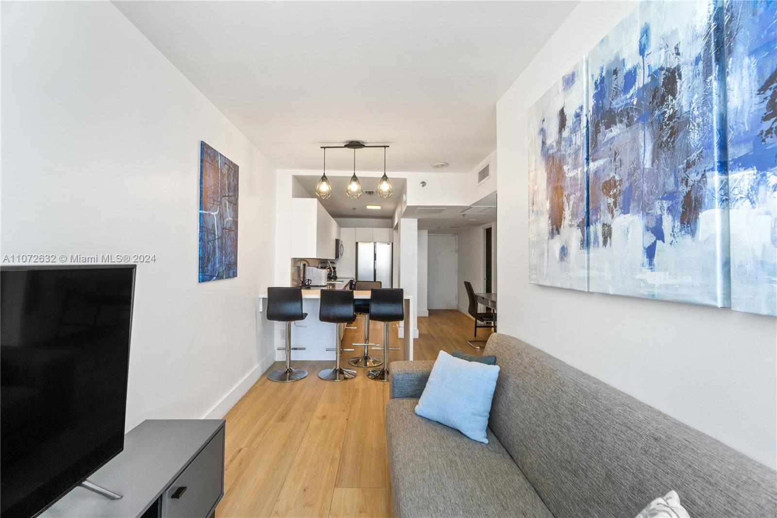 A living room with a gray sofa, a breakfast bar, and abstract wall art — 100 Lincoln Rd # 1627, Miami Beach FL 33139, MIAMI BEACH, FL