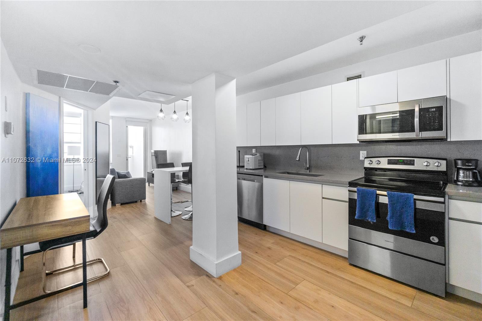 A modern kitchen features white cabinets, stainless steel appliances, and wood-look flooring — 100 Lincoln Rd # 1627, Miami Beach FL 33139, MIAMI BEACH, FL