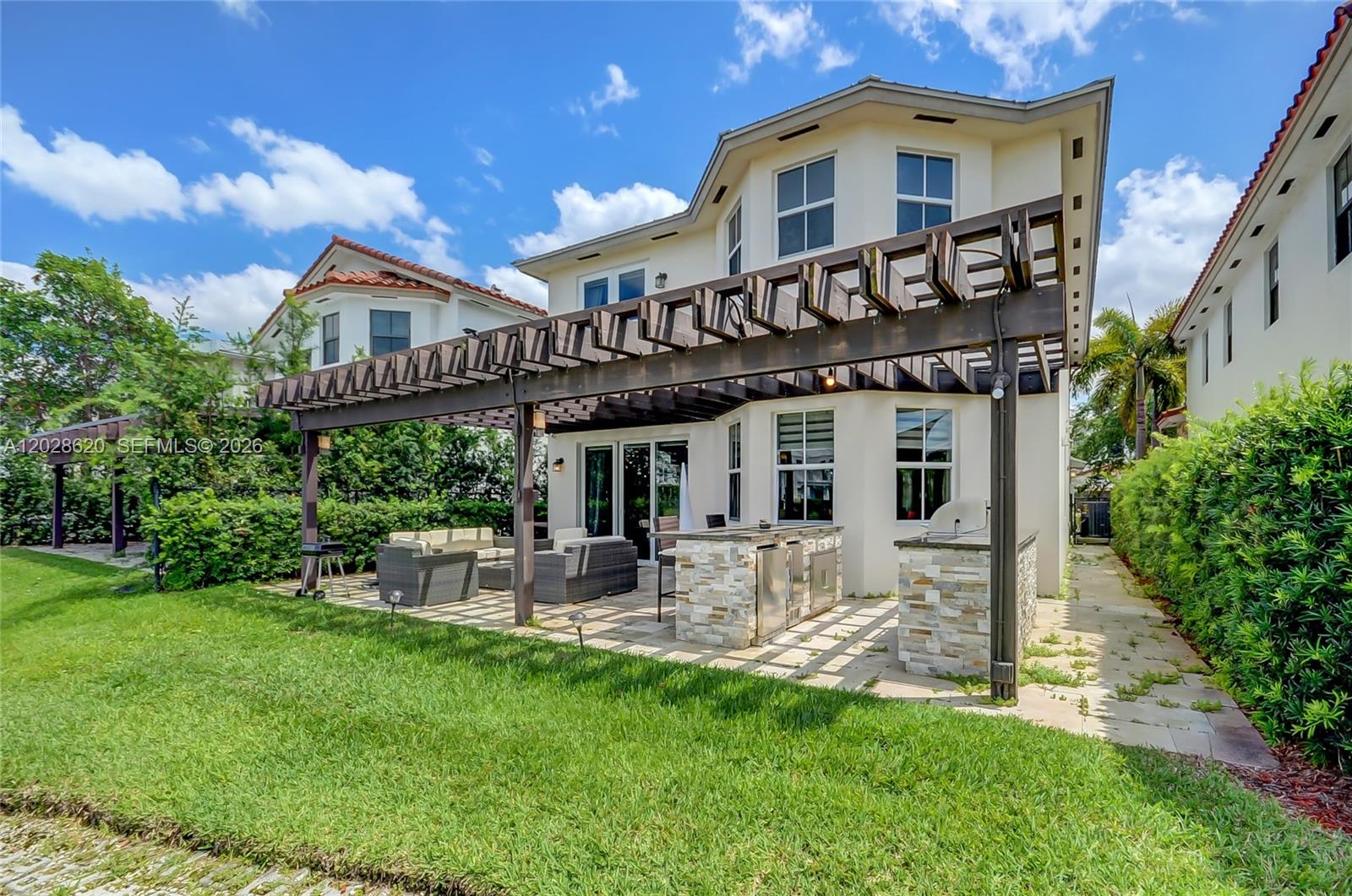 A patio features wicker furniture, a glass-topped table, and a wooden pergola overhead — 10555 NW 69th Ter, Doral FL 33178, DORAL, FL