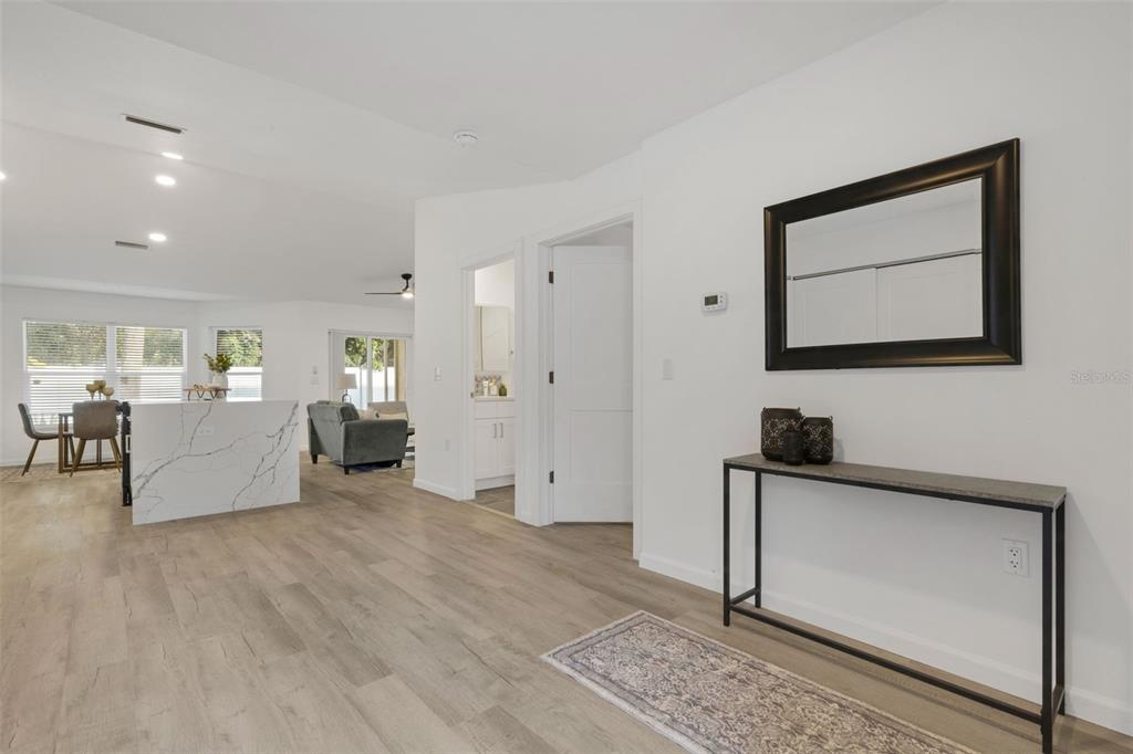 A bright entryway features light wood flooring, a console table, and a view into the kitchen — 606 MARCUS STREET UNIT 26, VENICE, FL