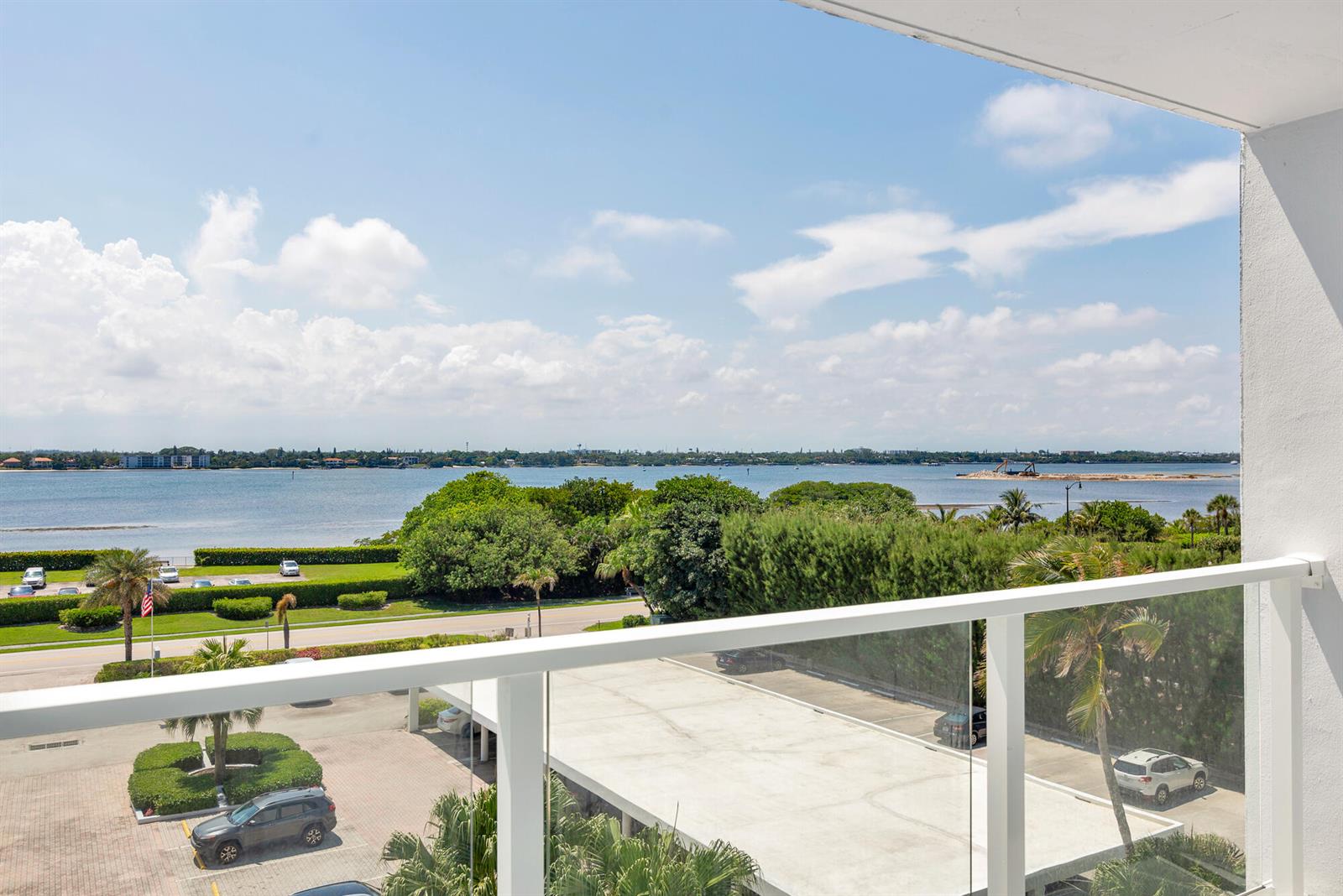 A balcony view overlooking a parking lot, green landscaping, and a large body of water — 3450 S Ocean Boulevard # 4270, Palm Beach FL 33480, PALM BEACH, FL