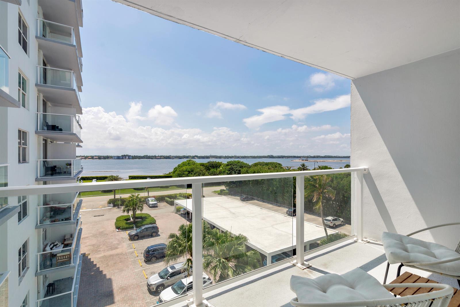 A high-rise balcony overlooks a parking lot, palm trees, and a body of water — 3450 S Ocean Boulevard # 4270, Palm Beach FL 33480, PALM BEACH, FL