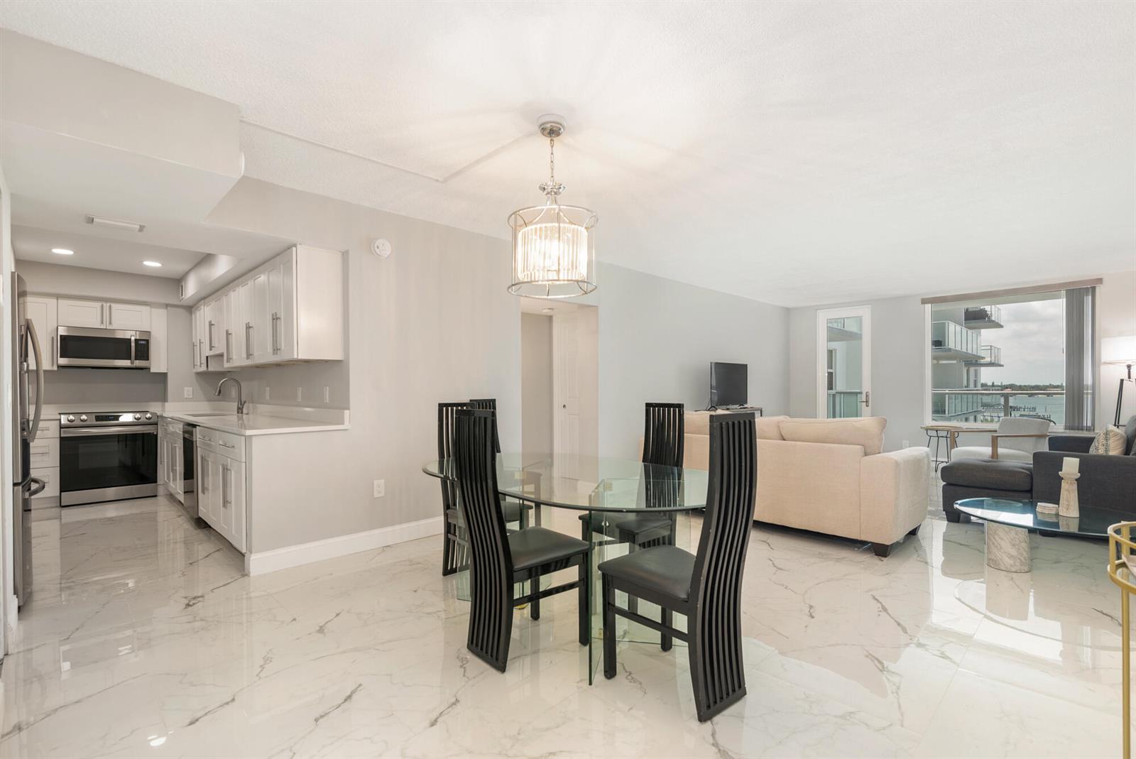 A dining area and kitchen with white cabinets, marble-look floors, and a glass table — 3450 S Ocean Boulevard # 4270, Palm Beach FL 33480, PALM BEACH, FL