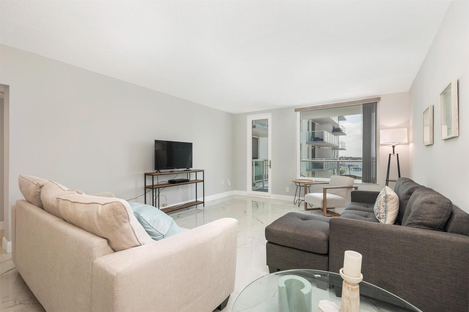 A living room features light-colored walls, marble-look tile flooring, two sofas, and a balcony view — 3450 S Ocean Boulevard # 4270, Palm Beach FL 33480, PALM BEACH, FL