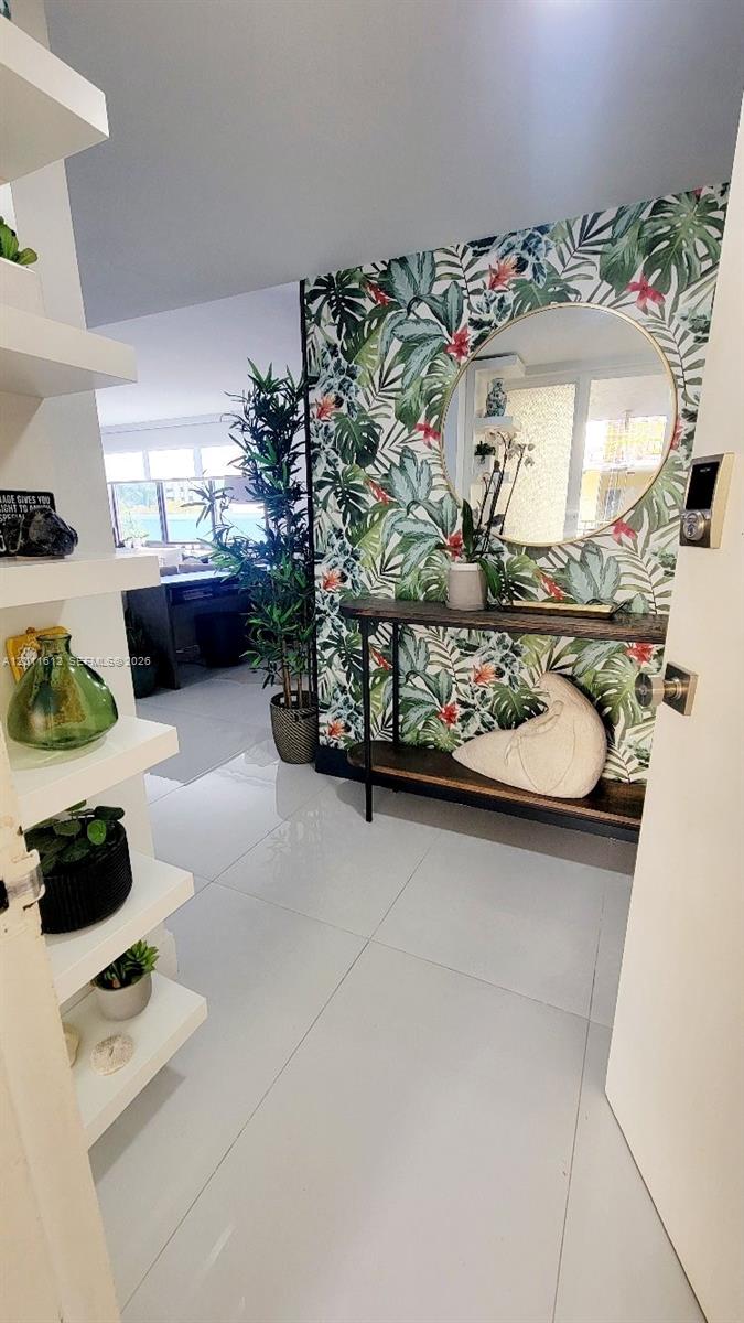 An entryway features tropical wallpaper, a round mirror, a console table, and white shelving — 250 Galen Dr # 43, Key Biscayne FL 33149, KEY BISCAYNE, FL