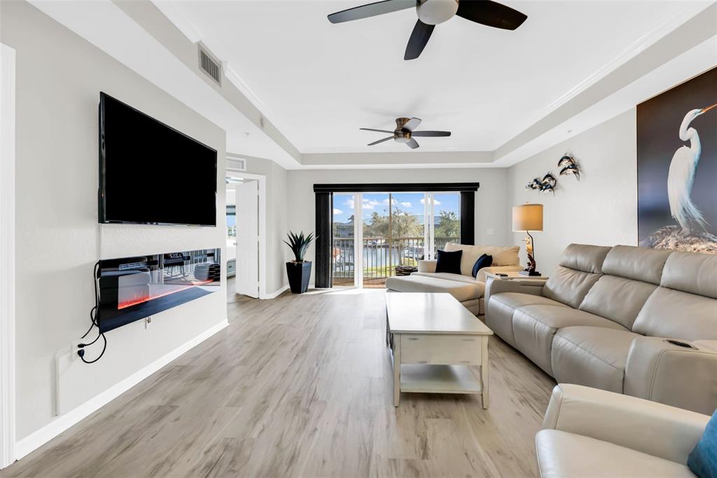 A living room features light wood flooring, a wall-mounted television, and a sliding glass door — 3322 PURPLE MARTIN DRIVE UNIT 125, PUNTA GORDA, FL
