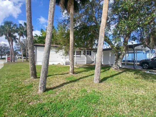 A white mobile home with a carport and palm trees in the front yard — 61 MOURNINGDOVE COURT, ELLENTON, FL