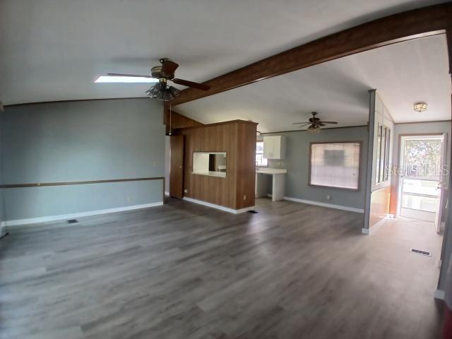 An open-concept living area features light wood-look flooring, a wood-paneled partition, and two ceiling fans — 61 MOURNINGDOVE COURT, ELLENTON, FL