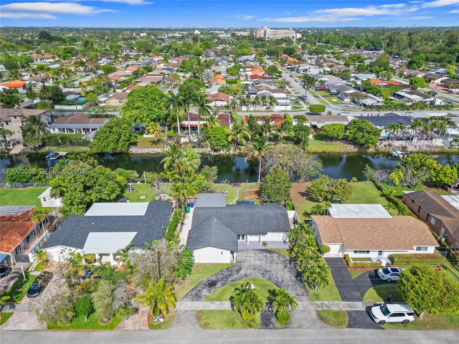 An aerial view shows suburban houses with driveways, green lawns, and a canal — 3921 SW 124th Ct, Miami FL 33175, MIAMI, FL