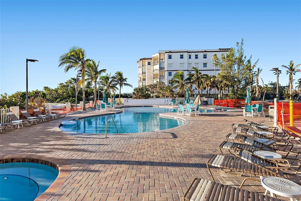 A swimming pool and hot tub are surrounded by lounge chairs and palm trees — 12000 GULF BOULEVARD UNIT 501-W, TREASURE ISLAND, FL