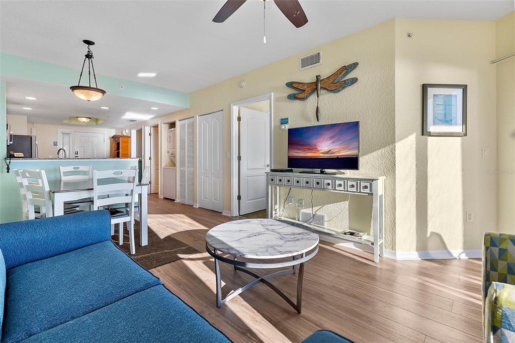 A living room with a blue sofa, marble coffee table, television, and adjacent dining area — 12000 GULF BOULEVARD UNIT 501-W, TREASURE ISLAND, FL
