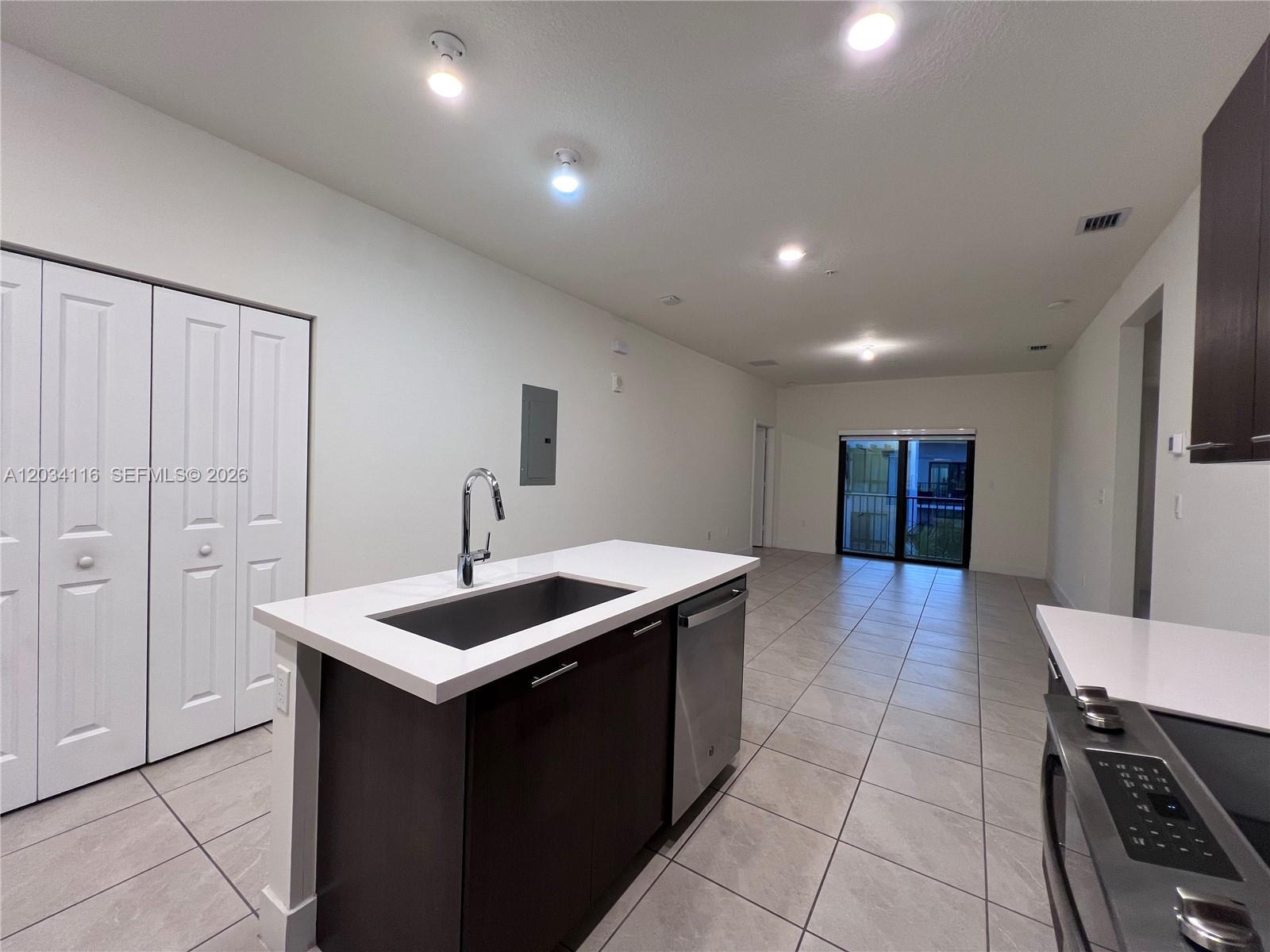 A kitchen island with a sink and dishwasher sits in an open-concept room with tile — 8265 NW 41st St # 405, Doral FL 33166, DORAL, FL