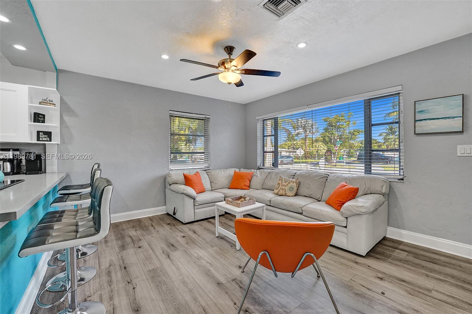 A living room features a sectional sofa, orange accent pillows, a ceiling fan, and bar seating — 529 NW 8th St, Dania Beach FL 33004, DANIA BEACH, FL