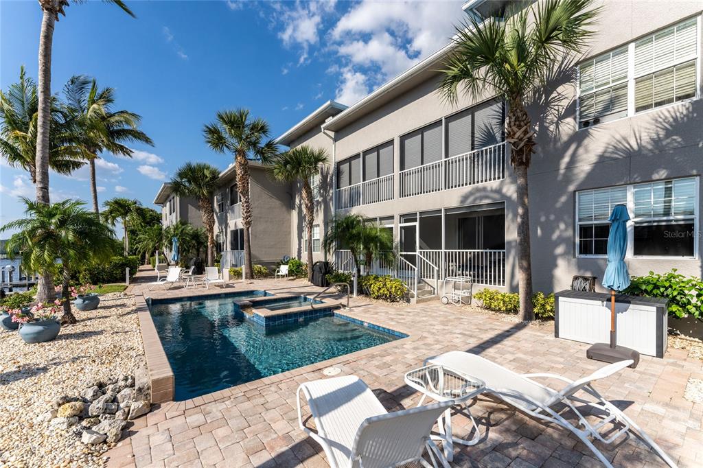 A swimming pool and hot tub sit on a patio outside a multi-story apartment building — 3311 WOOD THRUSH DRIVE UNIT 113, PUNTA GORDA, FL