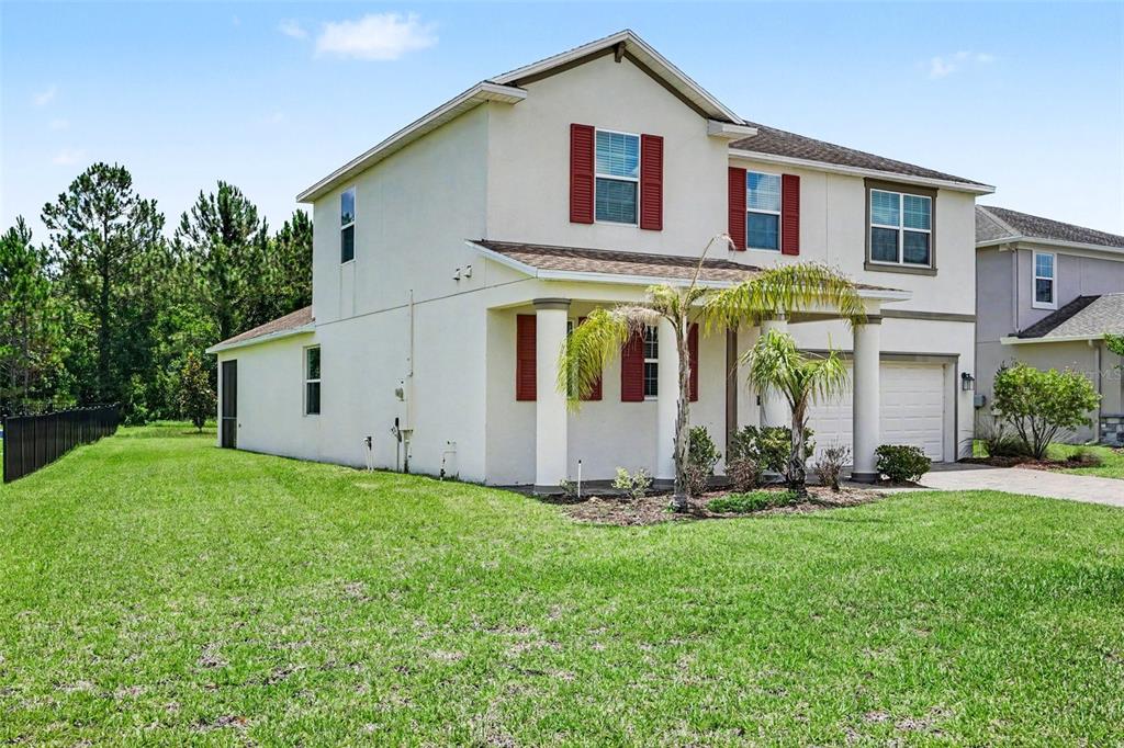 A two-story house with a beige stucco exterior, red shutters, and a front porch — 490 BRUNSWICK DRIVE, DAVENPORT, FL