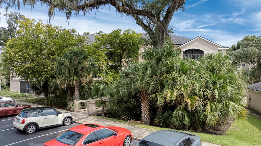 A multi-story apartment building exterior with palm trees, a wooden footbridge, and parked cars — 940 VILLAGE TRAIL UNIT 2-207, PORT ORANGE, FL