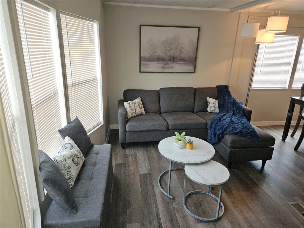 A living room features a gray sectional sofa, a small bench, and nested marble-topped tables — 3130 GREAT OAK STREET, WESLEY CHAPEL, FL