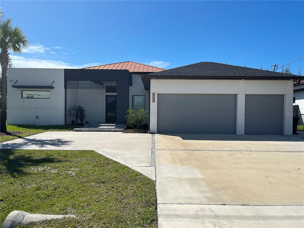 A modern single-story house features a two-car garage, a flat roof section, and a metal roof — 2106 SW 4TH STREET, CAPE CORAL, FL