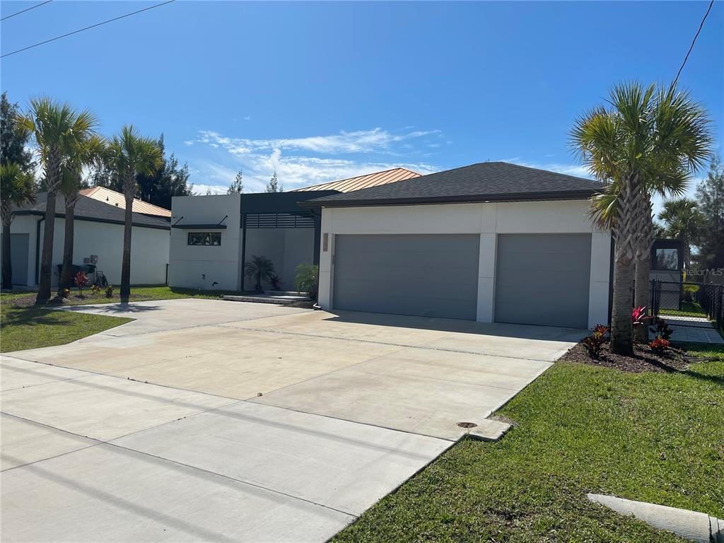 A modern single-story house features a two-car garage, a flat roof section, and palm trees — 2106 SW 4TH STREET, CAPE CORAL, FL