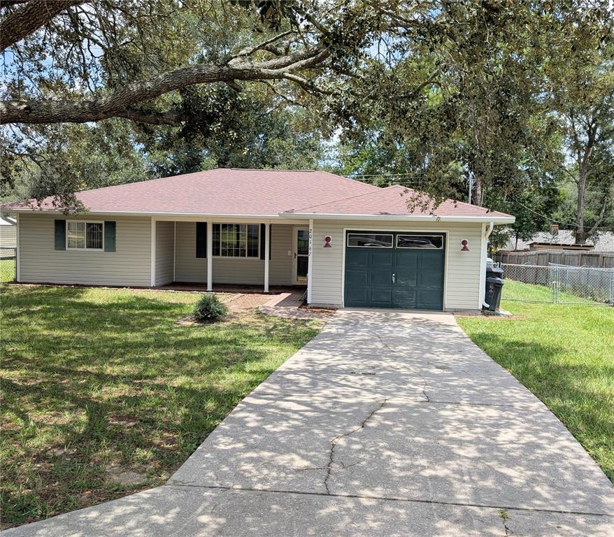 A single-story house with light siding, a dark garage door, and a concrete driveway — 20167 SW 81ST STREET, DUNNELLON, FL