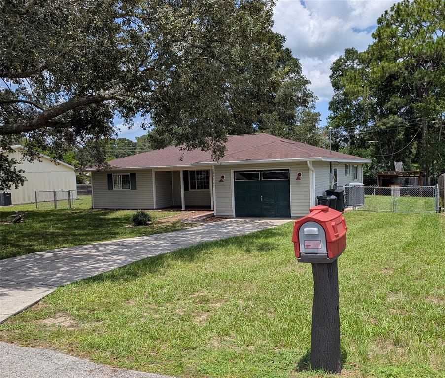 A single-story house with light siding, a dark roof, and a front-facing garage — 20167 SW 81ST STREET, DUNNELLON, FL