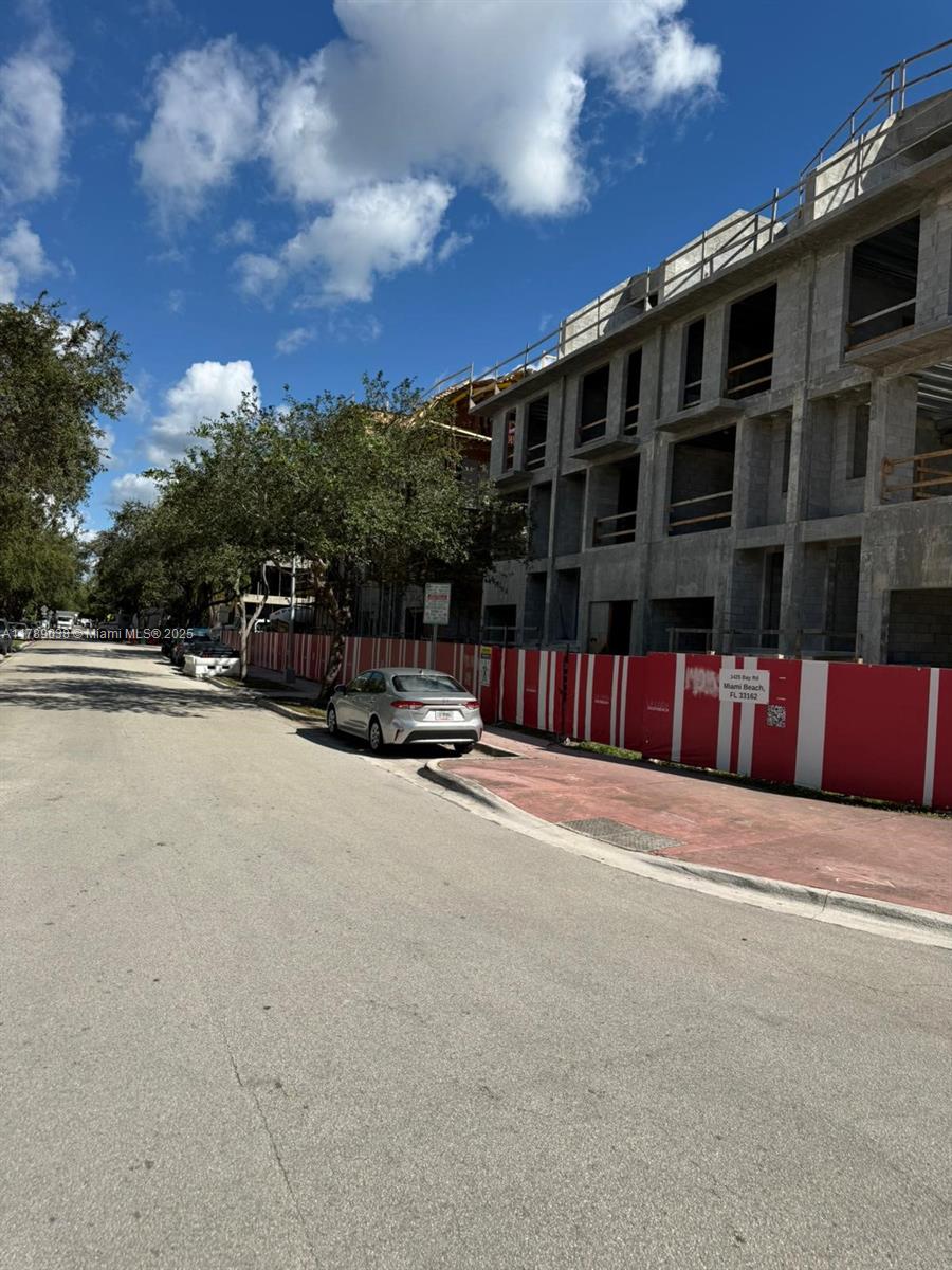 A multi-story concrete building under construction stands behind a red and white construction fence — 1425 Bay Rd, Miami Beach FL 33139, MIAMI BEACH, FL
