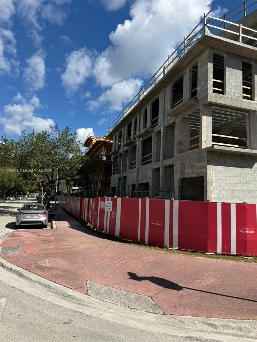 A multi-story concrete building under construction is enclosed by a red and white construction fence — 1425 Bay Rd, Miami Beach FL 33139, MIAMI BEACH, FL