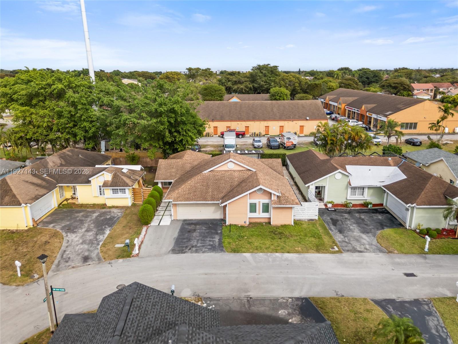 An aerial view shows three suburban houses with driveways and a nearby commercial building — 14145 SW 100th Ter, Miami FL 33186, MIAMI, FL