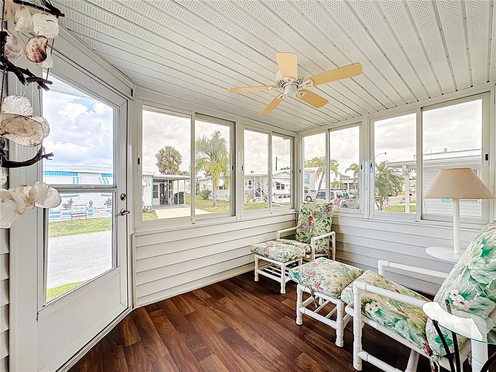 A sunroom features wood-look flooring, white paneled walls, a ceiling fan, and floral patio furniture — 80 DEL RIO DRIVE, PALMETTO, FL