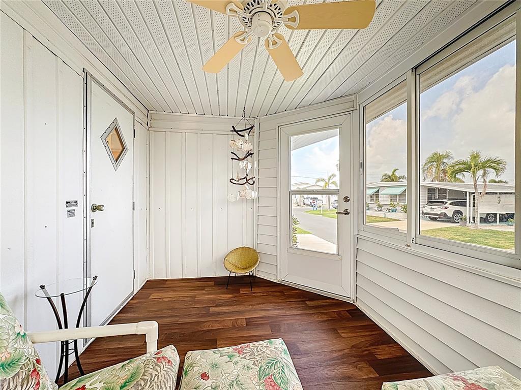 A sunroom features wood-look flooring, a ceiling fan, white paneled walls, and large windows — 80 DEL RIO DRIVE, PALMETTO, FL