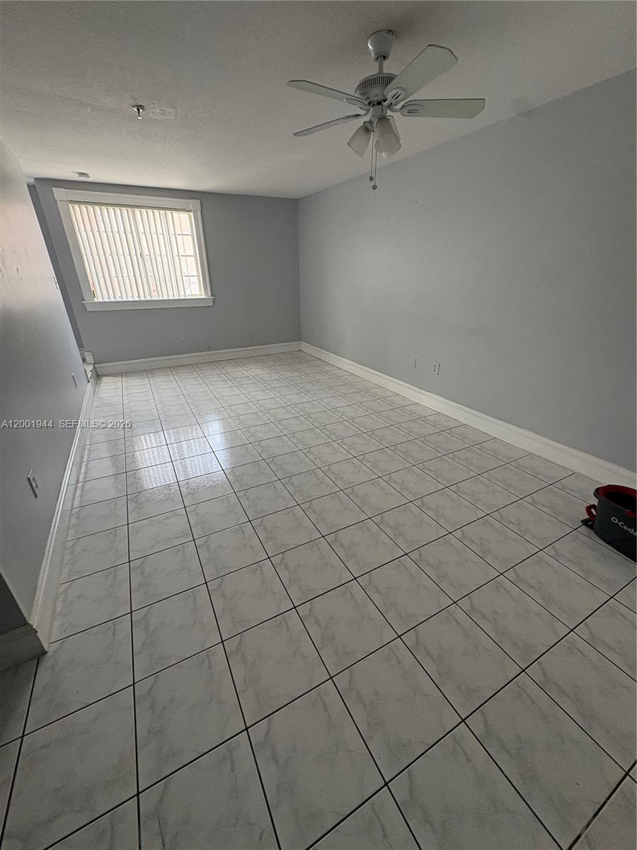 An empty room features light gray walls, white baseboards, and white marble-patterned tile flooring — 12035 SW 14th St # 105, Miami FL 33184, MIAMI, FL