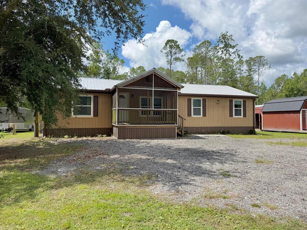 A house with a front porch sits on a large, grassy lot surrounded by trees — 5171 MAHOGANY BOULEVARD, BUNNELL, FL