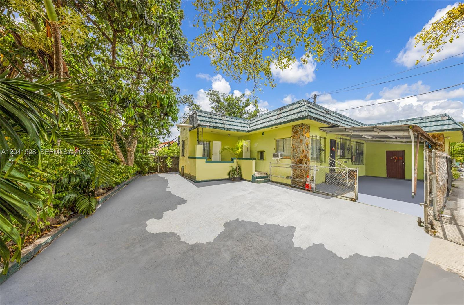 A yellow single-story house with a green tiled roof and a paved driveway — 1477 NW 2nd St, Miami FL 33125, MIAMI, FL