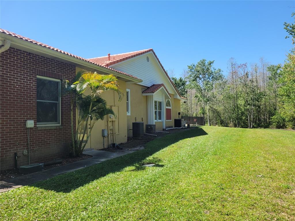 The exterior of a brick and stucco house features a lawn and air conditioning units — 3150 APPALOOSA COURT, KISSIMMEE, FL