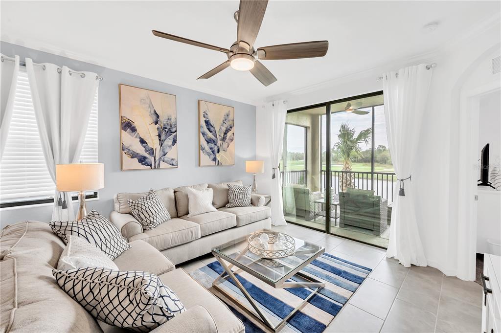 A living room features a beige sofa, a glass coffee table, and a sliding glass door — 18114 GAWTHROP DRIVE UNIT 201, LAKEWOOD RANCH, FL