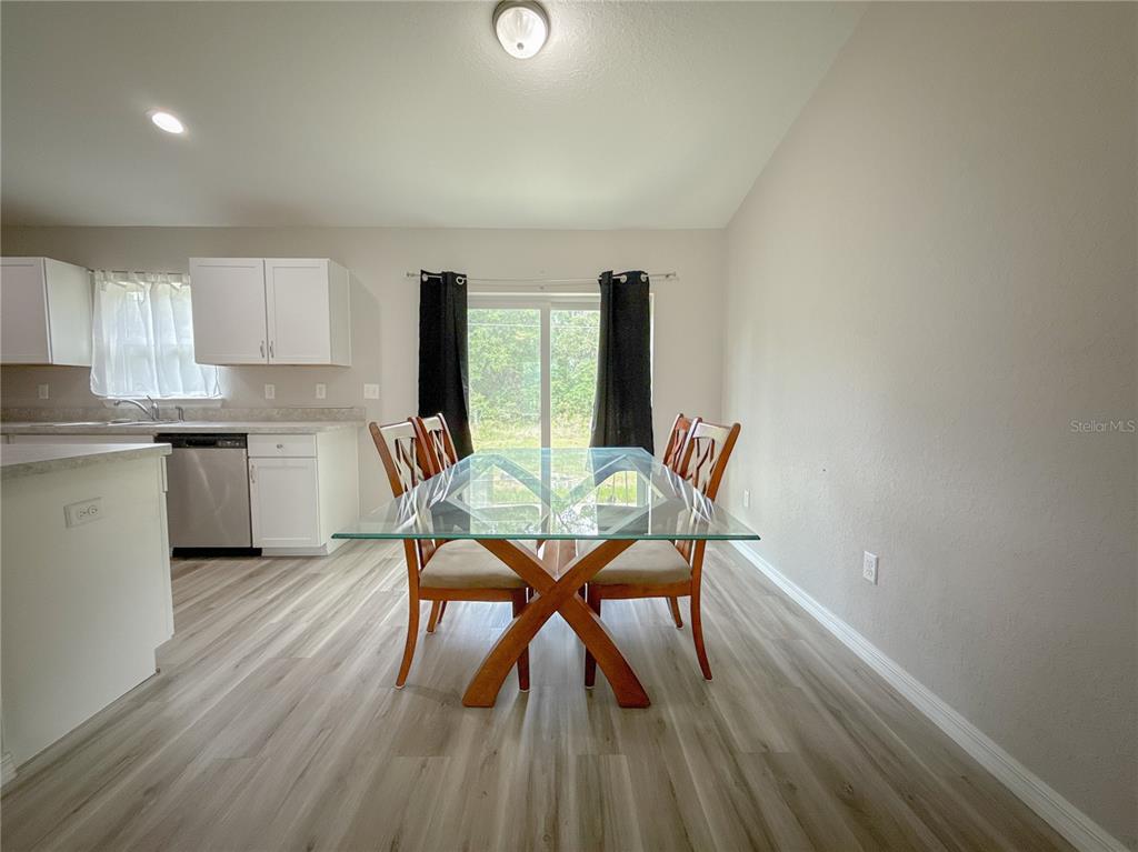 A dining area features a glass-topped table, wooden chairs, and light wood-look flooring — 15434 SW 29TH TERRACE ROAD, OCALA, FL