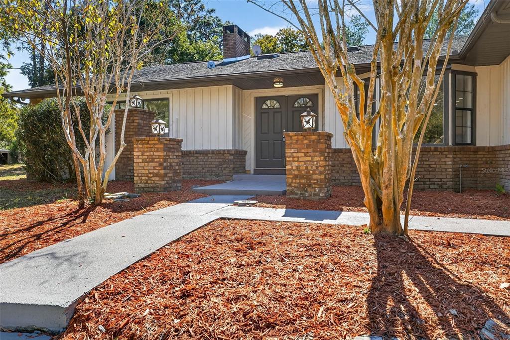 A single-story house features a brick and vertical siding exterior with a double front door — 14252 TRINITY ROAD, BROOKSVILLE, FL