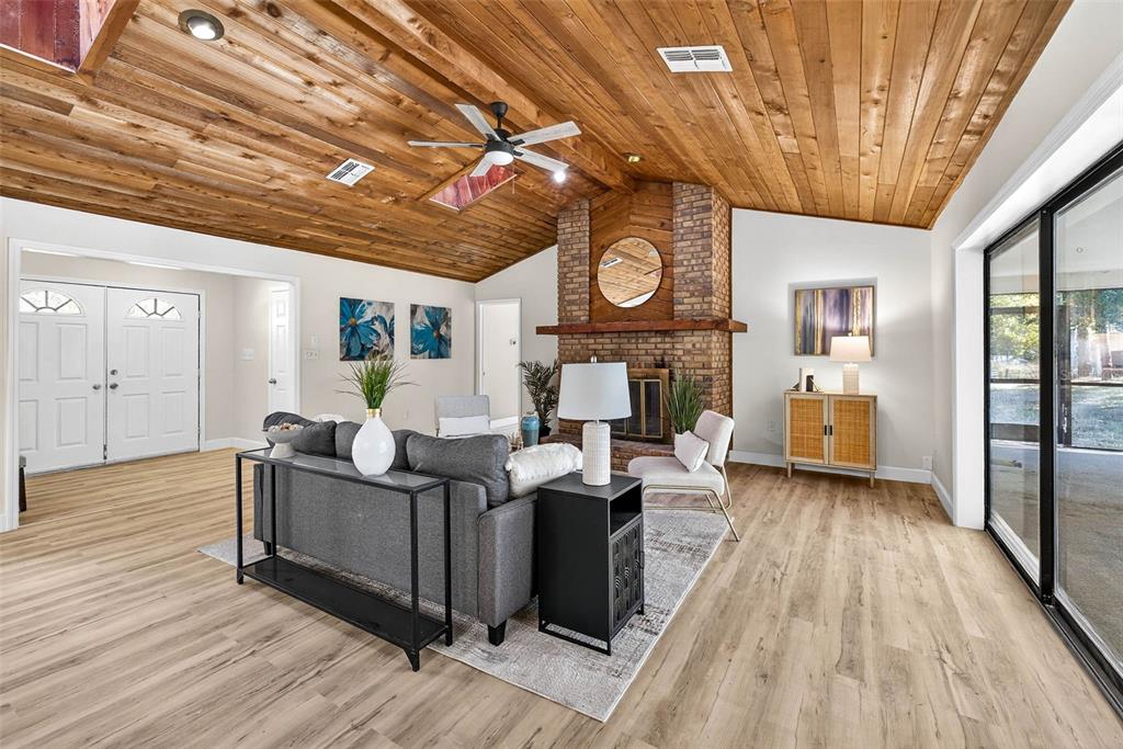 A living room features a vaulted wood-plank ceiling, brick fireplace, and light wood-look flooring — 14252 TRINITY ROAD, BROOKSVILLE, FL