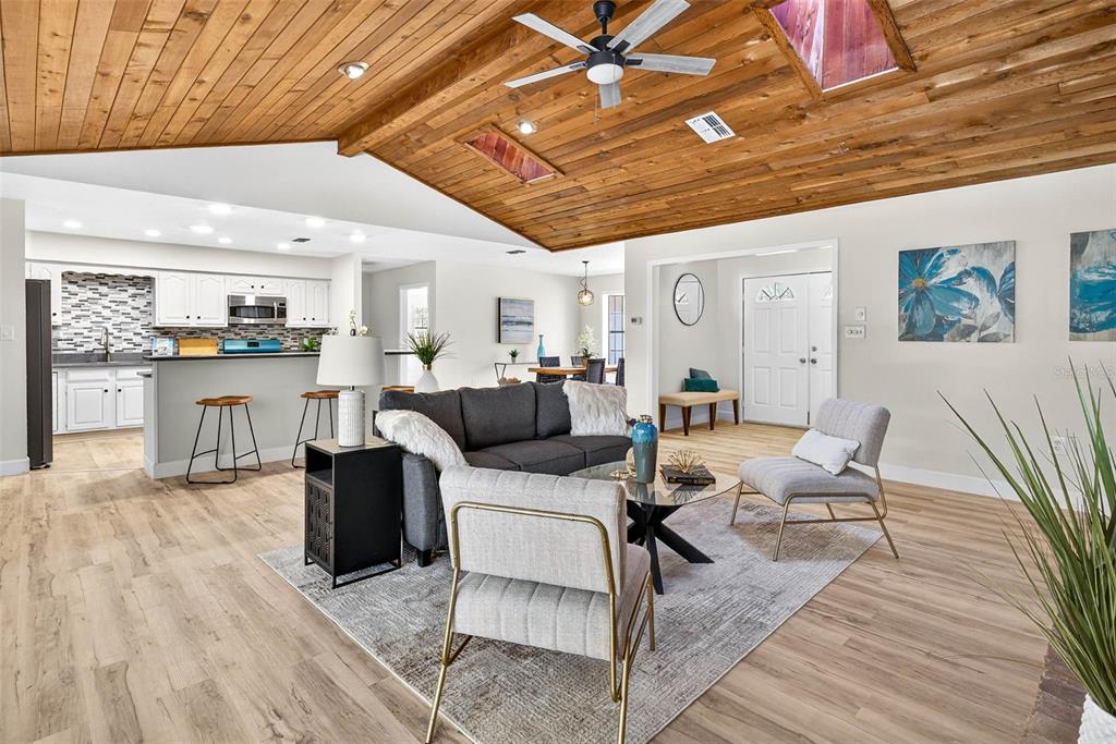 A living room with a wood-paneled vaulted ceiling opens to a kitchen and dining area — 14252 TRINITY ROAD, BROOKSVILLE, FL