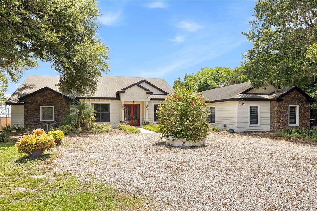 A single-story house with cream siding, a red double front door, and a stone walkway — 10355 TROUT ROAD, ORLANDO, FL