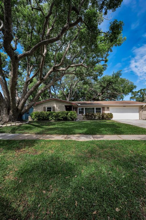 A single-story house with a white garage and large trees in the front yard — 1368 WILLIAMS DRIVE, CLEARWATER, FL